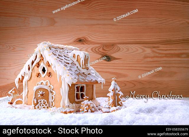 Gingerbread house on white snow isolated on the wooden background.Christmas background