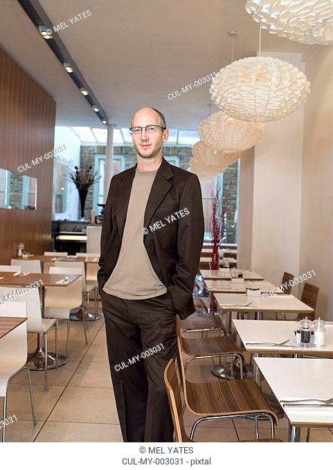 Mature man standing in empty restaurant, smiling, portrait