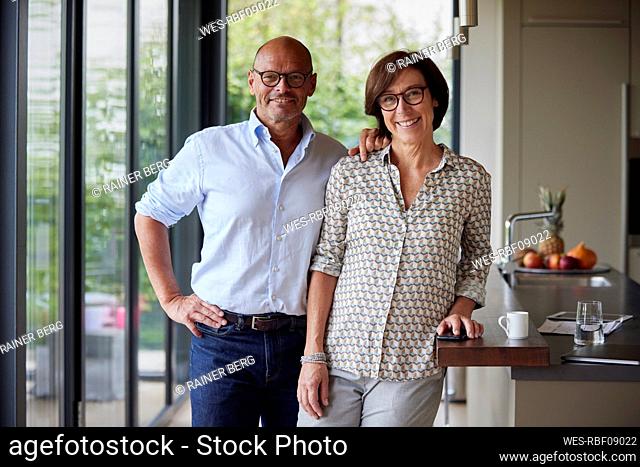 Happy senior couple standing together by kitchen island at home
