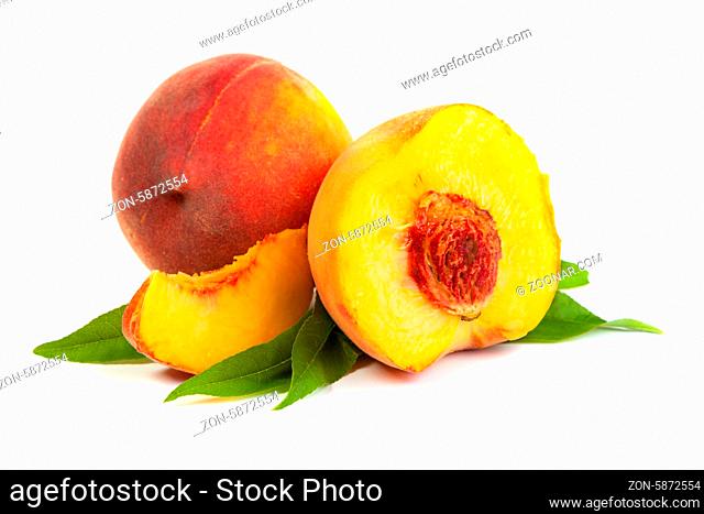 Three perfect, ripe peaches with a half and slices isolated on a white background
