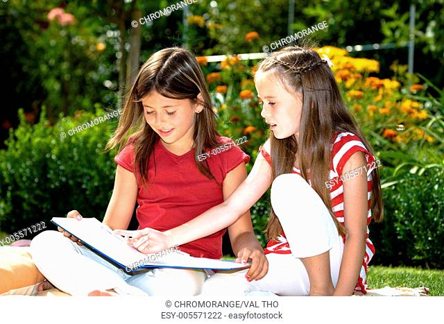 girls reading a book in the garden