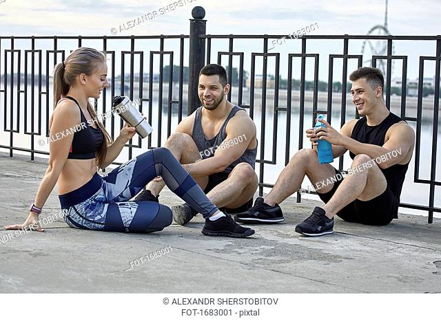 Young athletes resting on footpath by railing
