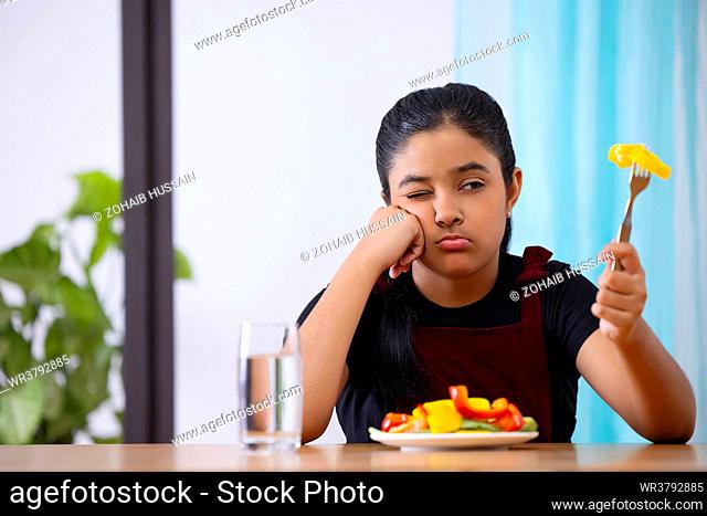 Portrait of a little girl expressing unhappiness over a plate of vegetable salad