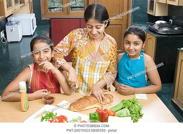 Close-up of a mid adult woman making sandwiches with her daughters