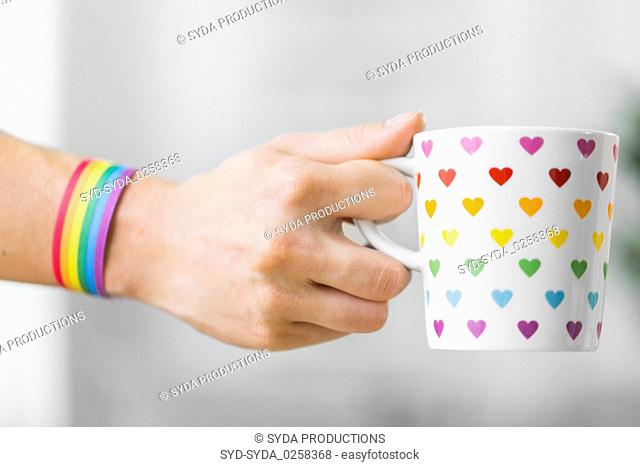 hand with cup of cacao and gay awareness wristband