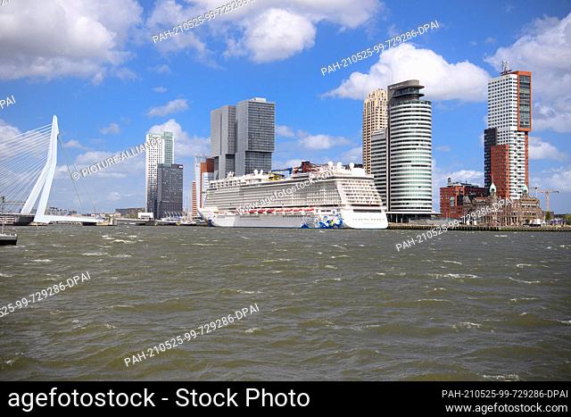 21 May 2021, Netherlands, Rotterdam: The cruise ship ""Norwegian Escape"" is moored on the banks of the Maas next to the high-rise buildings De Rotterdam...
