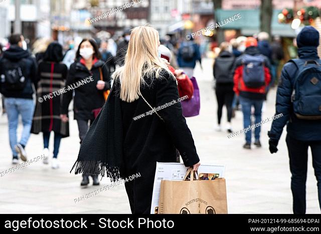 14 December 2020, Lower Saxony, Göttingen: Passers-by walk through the city centre with shopping bags. From 16.12.2020, the new tightened rules for the...