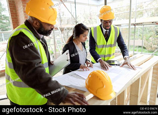 Architects and engineer looking at blueprints at construction site
