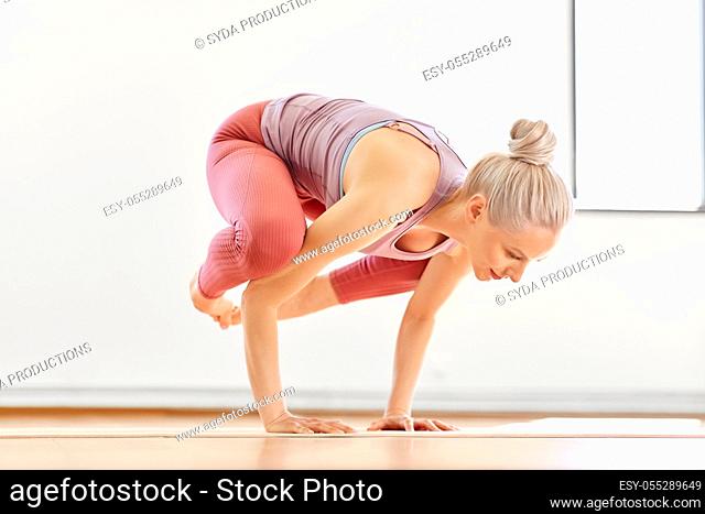 young woman doing crane pose at yoga studio