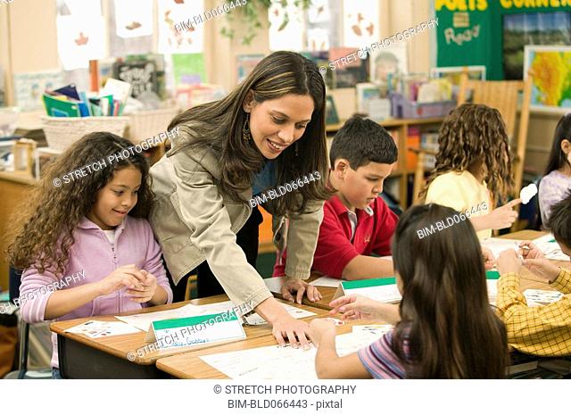 Hispanic school teacher helping students