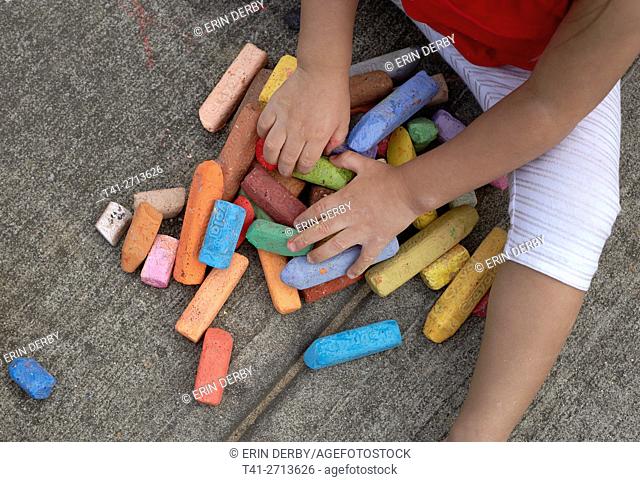 baby playing with chalk outside on concrete