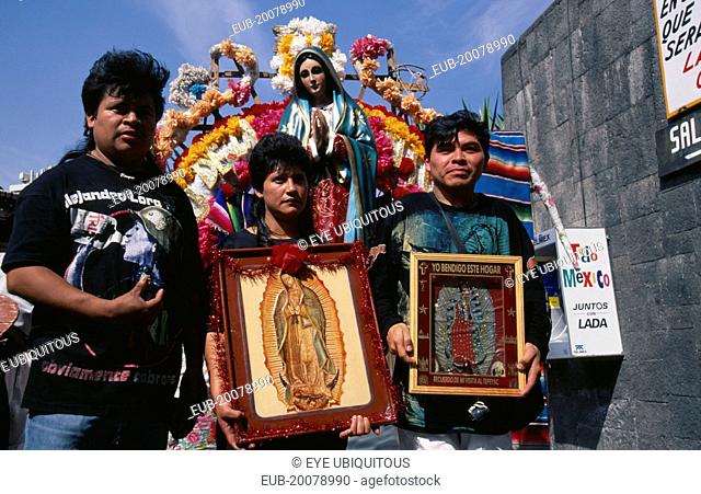 Pilgrims carrying icons and standing in front of statue of the Virgin Mary decorated with flowers at the Basilica de Guadeloupe for Day of Our Lady of...