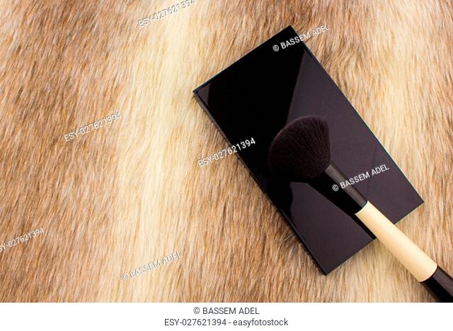 Makeup tools on Fur background / featuring eyeshadow palette, lipstick, makeup brushes on a fury background