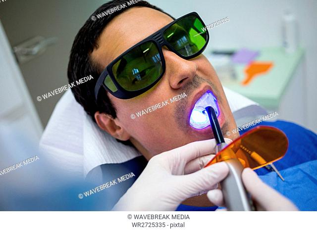 Dentist examining patients teeth with dental curing light