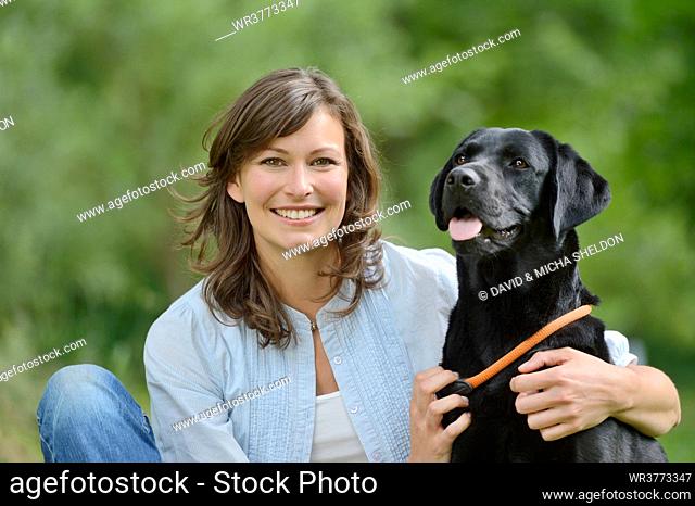 Woman with a black labrador on a meadow, Bavaria, Germany, Europe