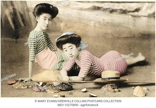 Two Geisha girls in elegant Western-style striped bathing costumes recline on a studio beach set