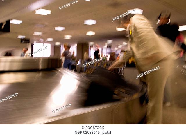 People picking up luggage from conveyor belt