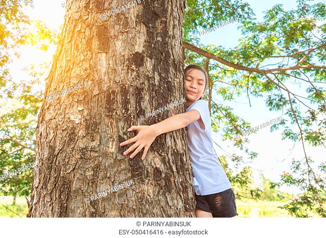 girl hugging tree trunk in park