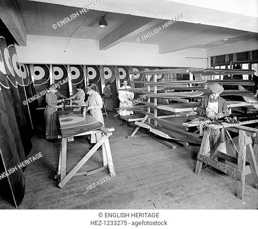 War work at Waring & Gillow, Hammersmith, London, 1916. Waring & Gillow's furniture factory was converted to war work. Here markings are painted onto wing...