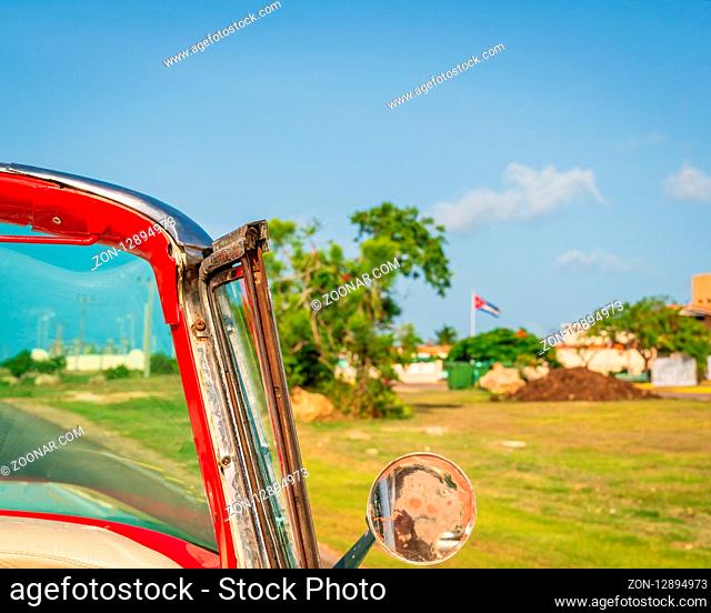 Cuba Varadero, view inside an old vintage classic american car on the right blurred Cuban flag, sunny day