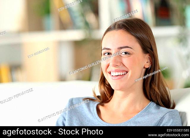 Happy teen looking at camera sitting on a couch in the living room at home