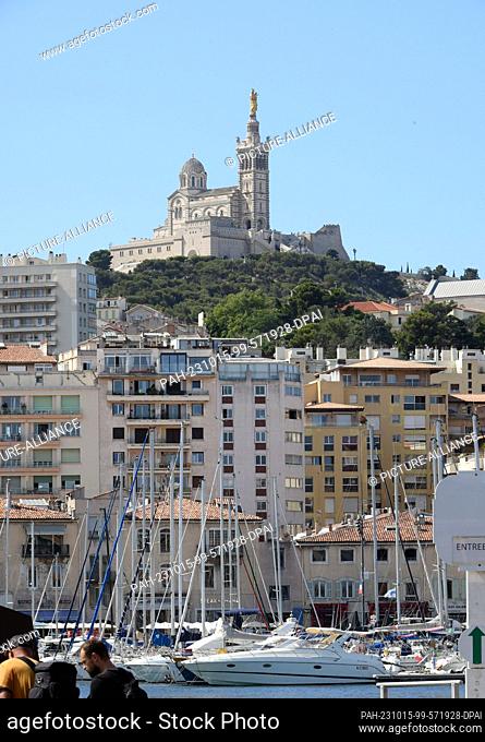 13 July 2023, France, Marseille: View over the harbor area in Marseille to the city and the church Notre-Dame de la Garde