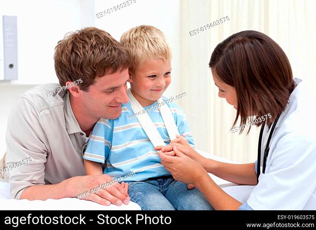 Smiling doctor examining little boy's hand