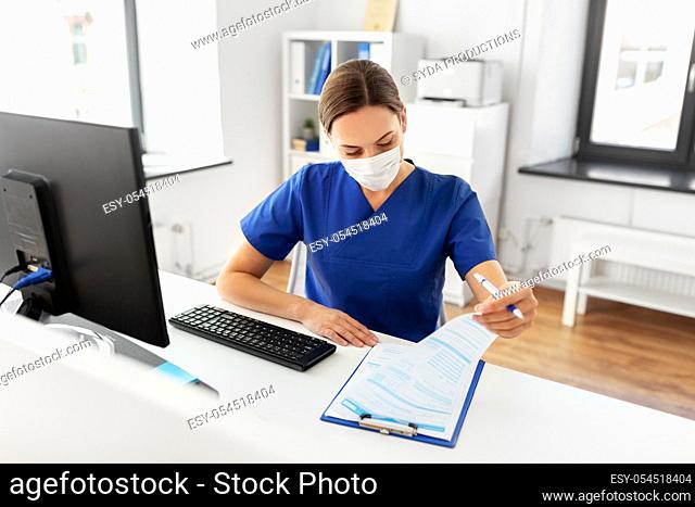 doctor or nurse in mask with clipboard at hospital