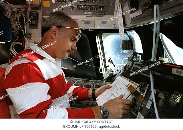 Astronaut William F. Readdy looks over a checklist at the commander's station on the Space Shuttle Atlantis' flight deck