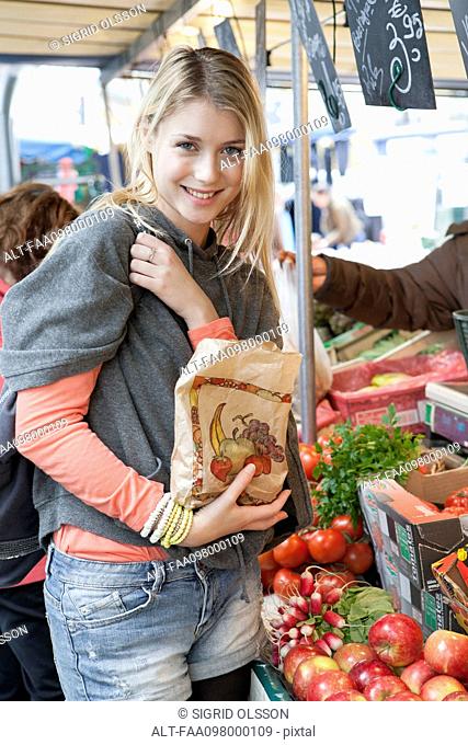 Young woman at greengrocer's buying fresh fruits and vegetables