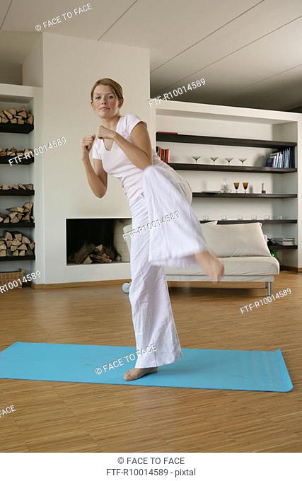 A blonde woman exercising in her hall, Tae Bo