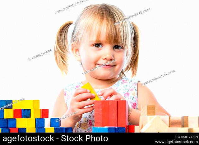 Close up portrait of infant playing building game with wooden blocks at table.Isolated on white background