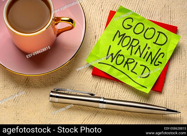 Good Morning world cheerful and positive memo - handwriting on a sticky note with cup of coffee