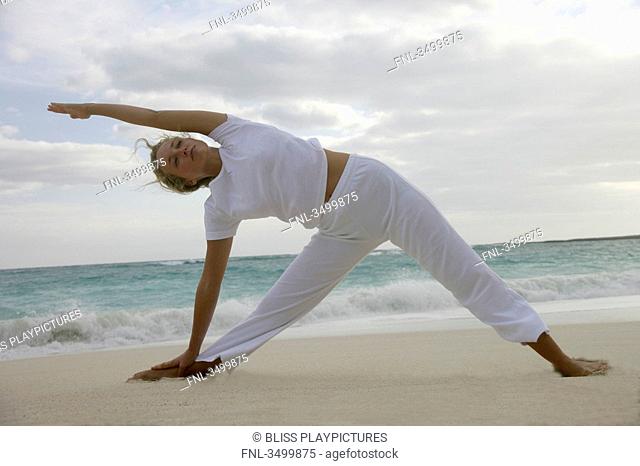 Young woman stretching on a beach, low angle view
