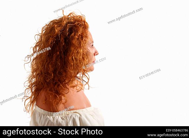 Portrait of middle aged woman with gorgeous hair posing in studio. Beautiful lady posing in profile in white dress isolated on white background