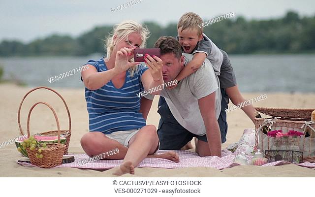 Beautiful family at beach making selfie with phone