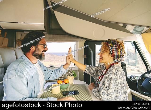 Happy mature caucasian couple enjoy time sitting inside a modern camper van. Off grid life and holiday vacation lifestyle. Tourism with vehicle
