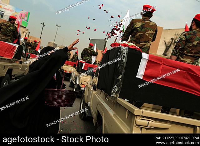 29 December 2021, Iraq, Baghdad: A woman throws flower petals on members of the Iraqi predominantly Shia Muslim Popular Mobilization Forces (PMF) as they parade...