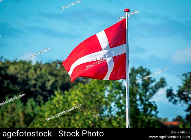Flag of Denmark in the wind with trees in the background
