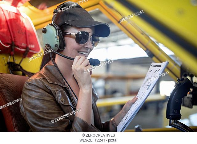 Female pilot inspecting light aircraft cockpit