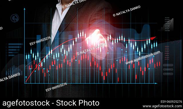 a businessman in a suit stands in front of a holographic graph with growing figures, business growth, high income. Trading on the stock exchange