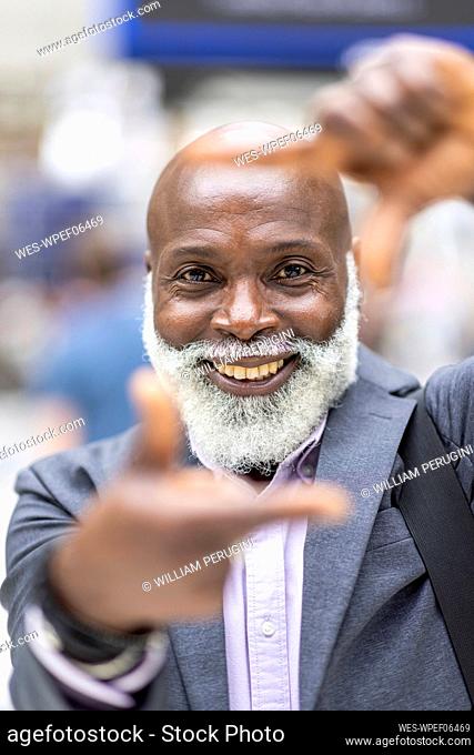 Smiling businessman looking through finger frame