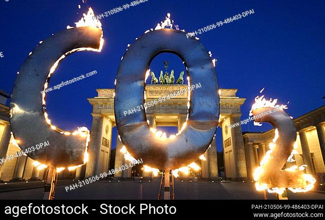 dpatop - 06 May 2021, Berlin: In a Greenpeace action, a CO-2 sign stands in front of the Brandenburg Gate with flames coming out of it