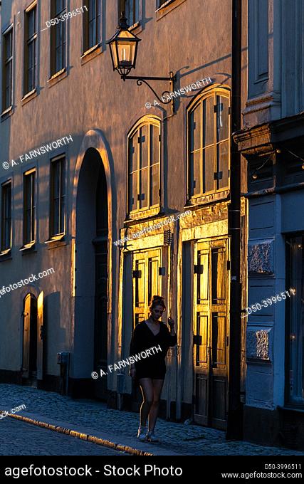 Stockholm, Sweden, A woman walks in the setting sun on lilla Nygatan on Gamla Stan or Old town