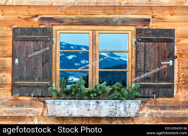 Vintage Window of old alpine house. Wooden rustic background. Reflections of snow spotted mountains in window glass