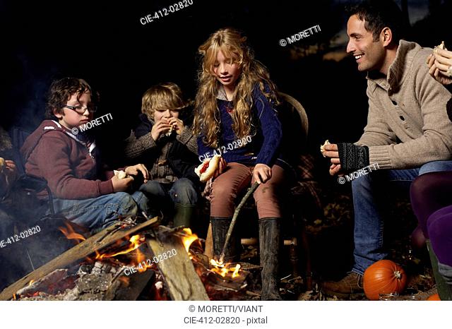 Family eating around campfire at night