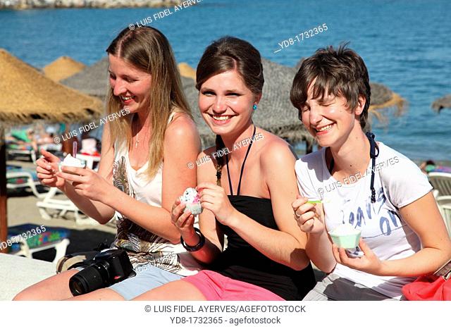 Young women eating ice cream on the promenade of Fuengirola, Malaga, Andalucia, Spain