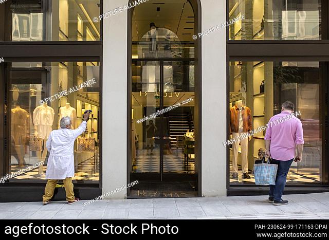 24 June 2023, Greece, Athen: A man cleans the windows of a clothing store in the center of the Greek capital. Greeks elect a new parliament on June 25, 2023