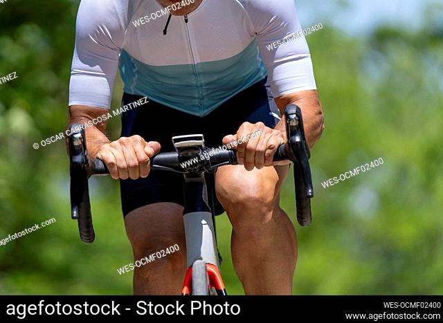 Athlete in sports clothing riding bicycle on sunny day