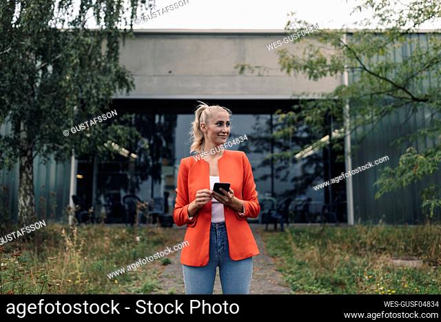 Young businesswoman with smart phone in company garden